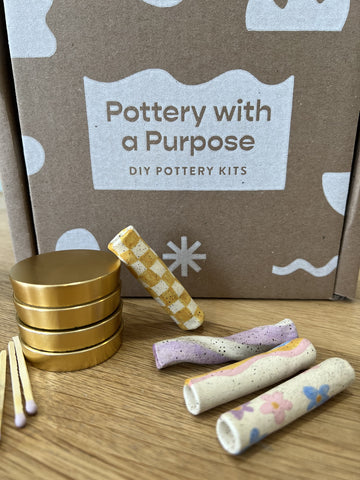 Brown Pottery with a Purpose box with four clay chillums and a gold grinder