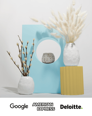 Two air dry clay vases with dried flowers, and a ceramic clay tealight candle holder sitting atop a blue photo prop.